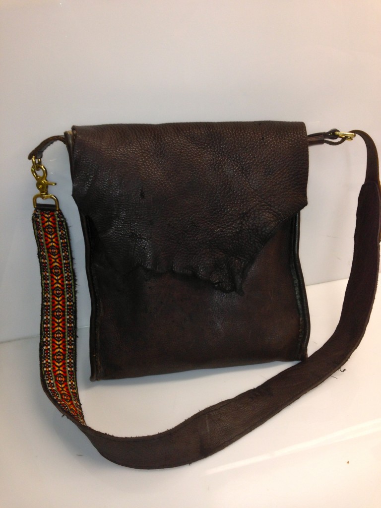 handmade leather cross-body bag with guitar strap on display