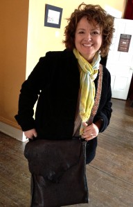 daughter posing with a leather hide cross-body bag with guitar strap made by her father, a former U.S. soldier
